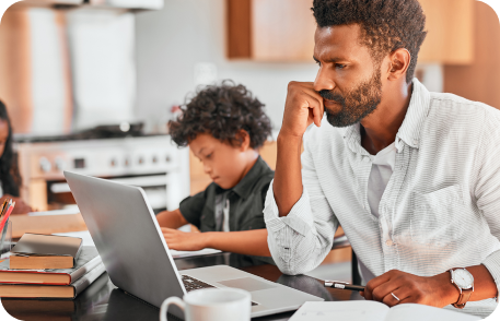 Man looking laptop next to kid.
